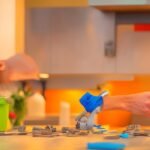 A focused close-up of a determined homeowner’s hands carefully peeling and aligning stylish adhesive backsplash tiles on a kitchen wall, surrounded by simple DIY tools like a level and scissors, captured with cinematic lighting and rich colors to highlight the texture and ease of installation in a warmly lit, real home setting.