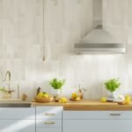 A bright, modern kitchen scene featuring a close-up of hands carefully applying sleek, geometric peel-and-stick backsplash tiles on a clean wall, with natural light highlighting the fresh, stylish transformation in progress.
